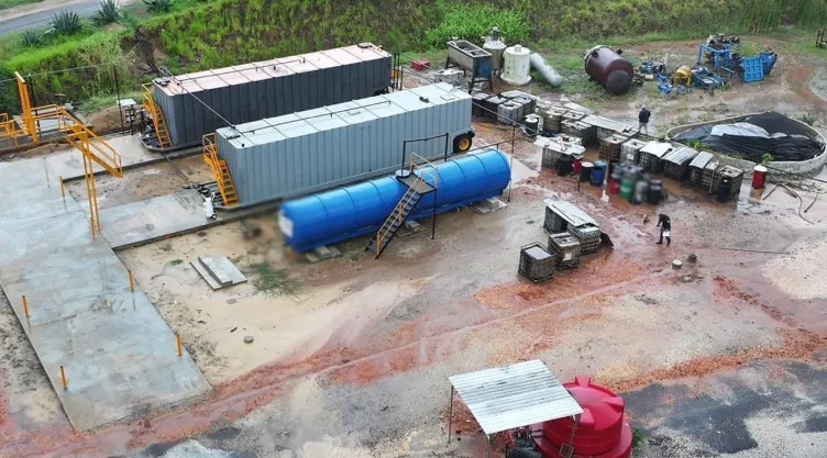 La imagen muestra tres grandes contenedores, uno de color azul y dos de color gris, además de varios tanques pequeños.