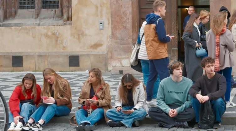 Adolescentes sentados con teléfonos celulares.