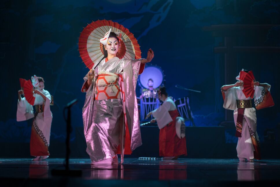 Traditional Japanese performance. Actresses in traditional white and red kimono and fox masks dancing with umbrella and fans.