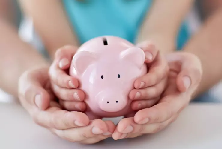 una familia sosteniendo un chanchito que almacena dinero