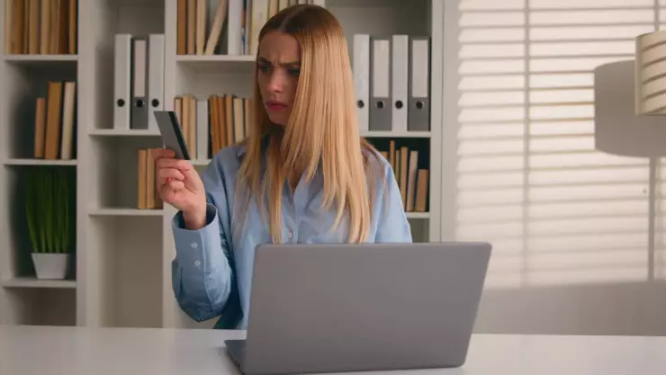 Una mujer confundida con su tarjeta en la mano