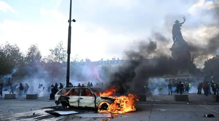 Un auto arde en París durante una protesta contra el alto costo de vida.