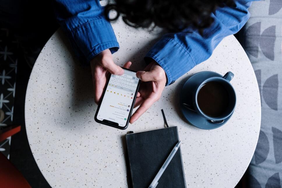 mujer en el celular con cafe y libreta