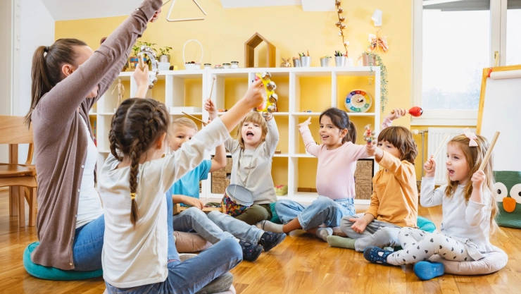 Una maestra y sus alumnos forman un círculo y alzan las manos