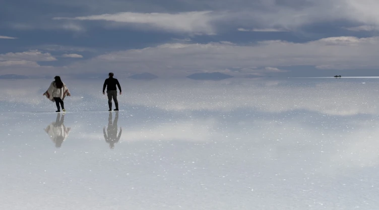 Turistas mexicanos caminan sobre el efecto espejo del Salar de Uyuni, Bolivia