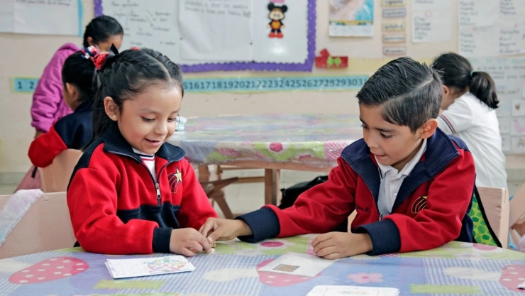 Becas de exención para estudiantes de escuelas privadas Edomex 2026; en la imagen se ven dos niños haciendo tareas en la escuela.