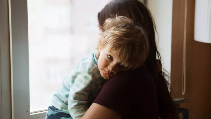 Una madre carga en sus brazos a su hijo