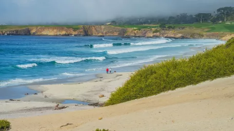 Unas personas caminan por la playa en Carmel, California.