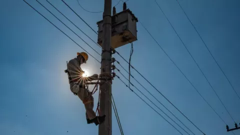 Empleado de la CFE realizando reconexión del servicio en un poste de energía eléctrica.