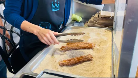 Churros ya preparados, siendo azucarados para su venta