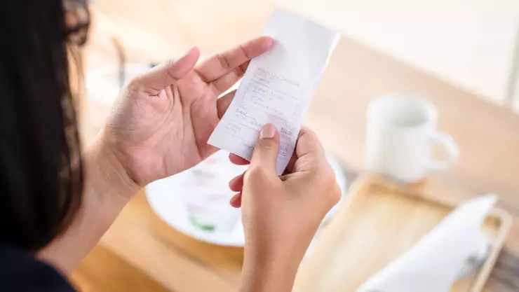 Una mujer mira la cuenta de un restaurante y nota que se incluye esta “tarifa de servicio” pero, ¿de qué se trata?