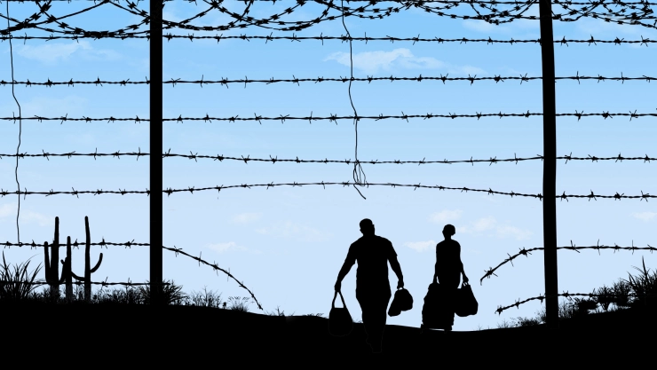 Inmigrantes cruzan una valla fronteriza.