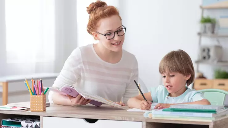 Una maestra asiste a un ni&ntilde;o que necesita aprendizaje especial para mejorar en su rendimiento escolar