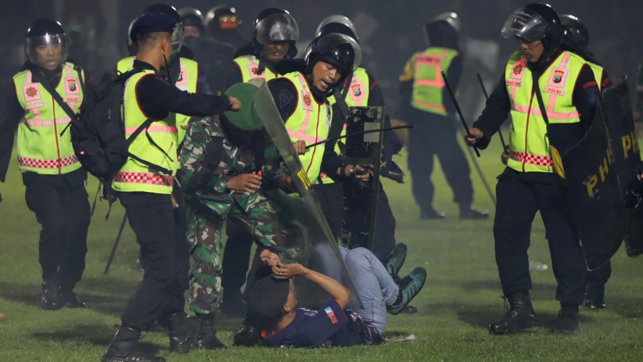 Policía detienen a un aficionado durante trifulcas en un partido de fútbol, en Indonesia.