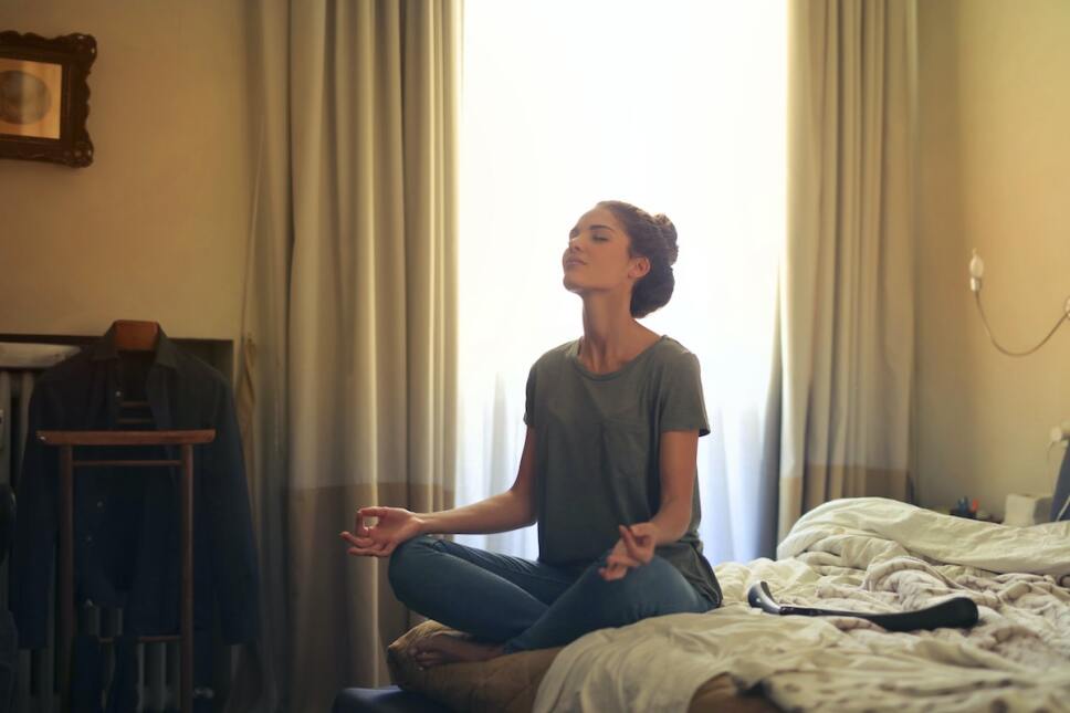 mujer joven meditando en su cama