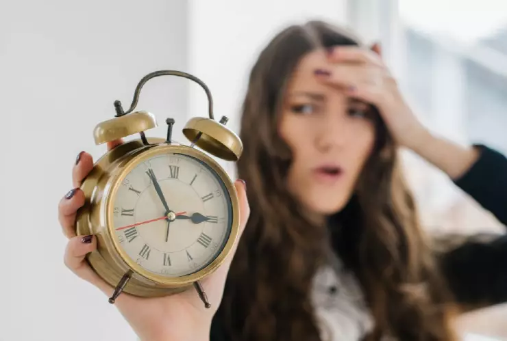 Una mujer sostiene un reloj y que indica la hora 