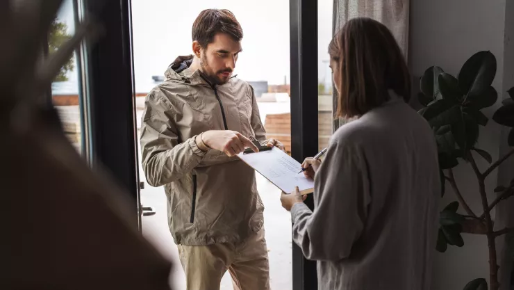 Una persona le pide a otra que llene una encuesta en la entrada de una casa.