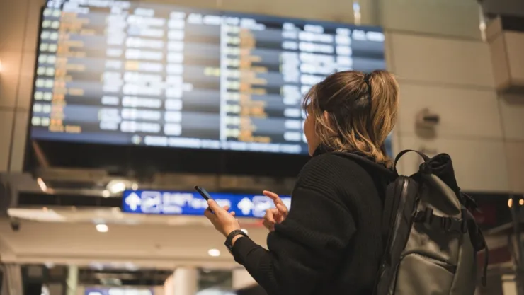 Una joven mira la pantalla de vuelos en un aeropuerto.