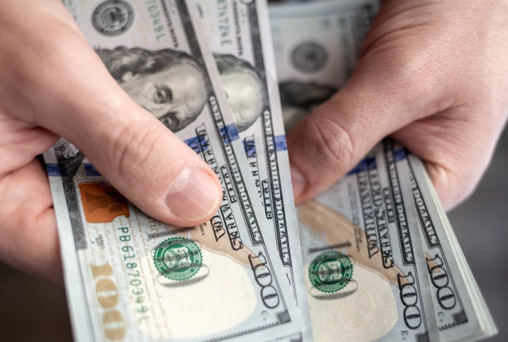 Persona cuenta varios billetes de 100 dólares