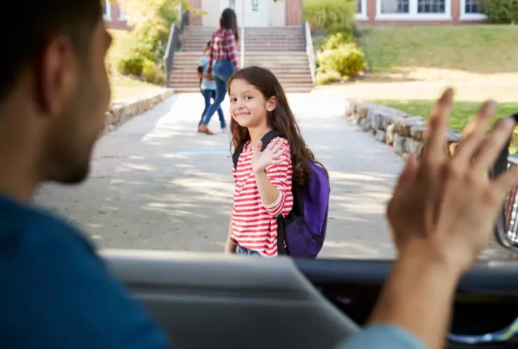 Un padre saluda a su hija en el ingreso de la escuela