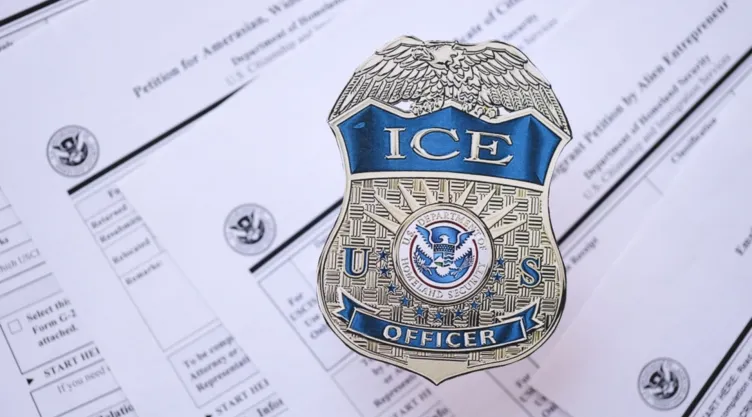 Una placa del ICE encima de formularios de migración.