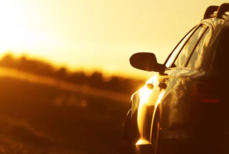 en el horizonte se observa un fuerte rayo de sol y en la parte inferior derecha un carro