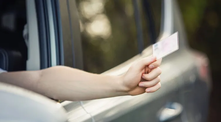 Una persona enseña su licencia de conducir.