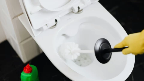 un retrete siendo limpiado con un cepillo.