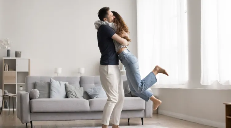 Una pareja se abraza en la sala de una casa.