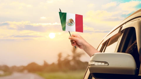 Mexicano ondea la bandera de su país por la ventanilla de su coche