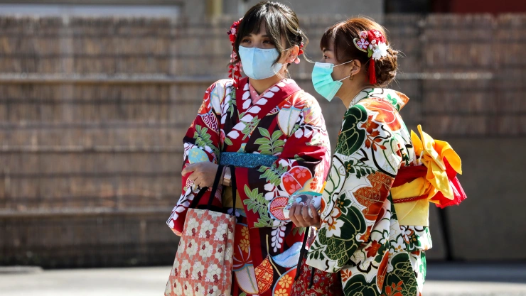Turistas con kimono y máscaras protectoras visitan el Templo Sensoji en el distrito de Asakusa en Tokio, Japón