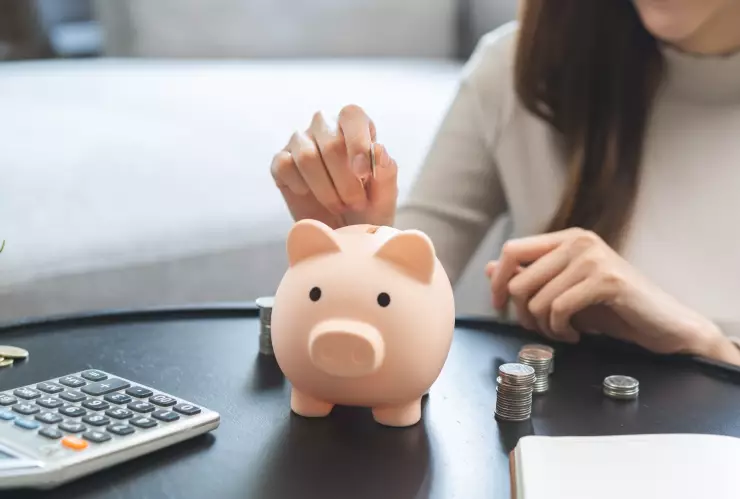 Una mujer coloca monedas en una alcancía