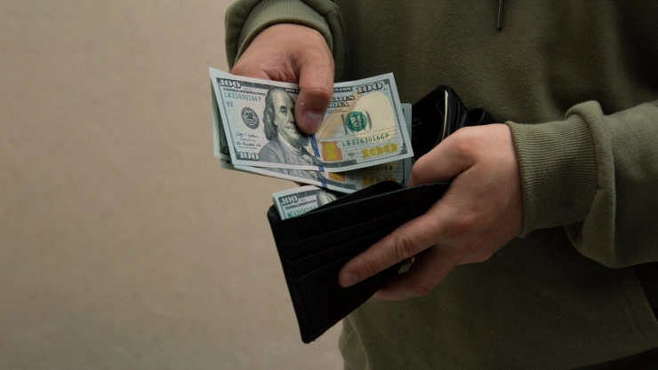 Hombre guarda billetes de 100 dólares en su billetera