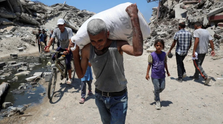 Un palestino lleva una bolsa con suministros de ayuda que ingresaron a Gaza a través de Israel, en Beit Lahia, norte de la Franja de Gaza.