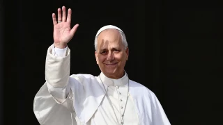 Papa León XIV usando un traje blanco y saludando desde el balcón de las bendiciones en 2025