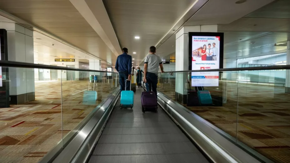 Dos personas recorren el pasillo de un aeropuerto.