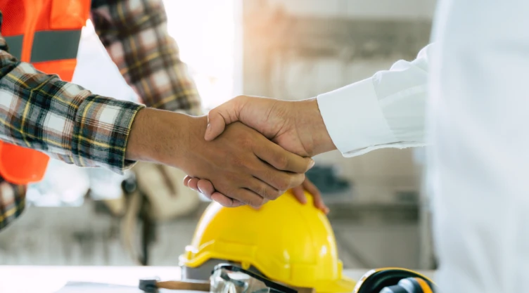 Trabajador de construcción estrecha manos con su jefe