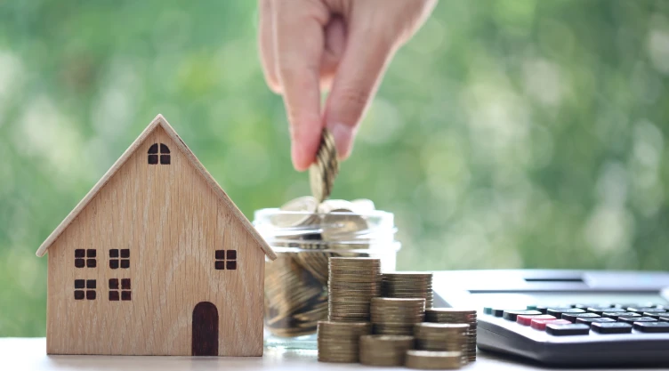 Una maqueta de vivienda y dinero alrededor.