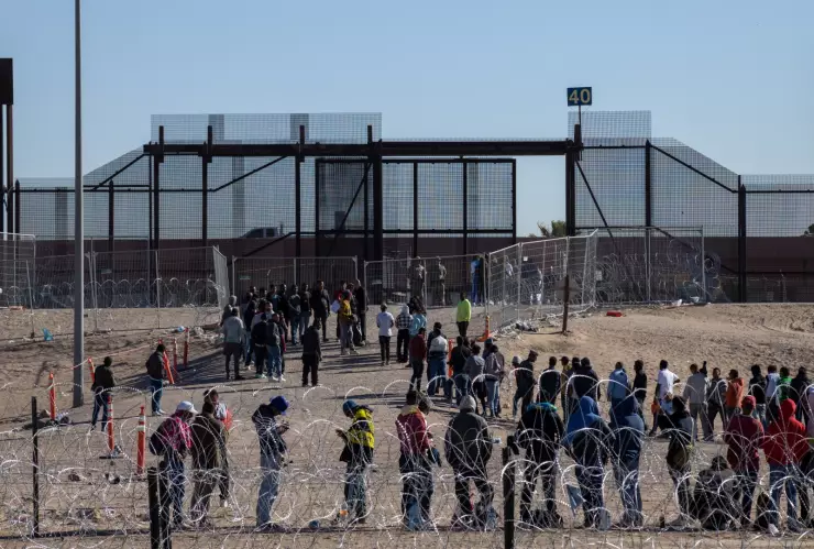 Personas hacen fila en la frontera entre México y Estados Unidos.