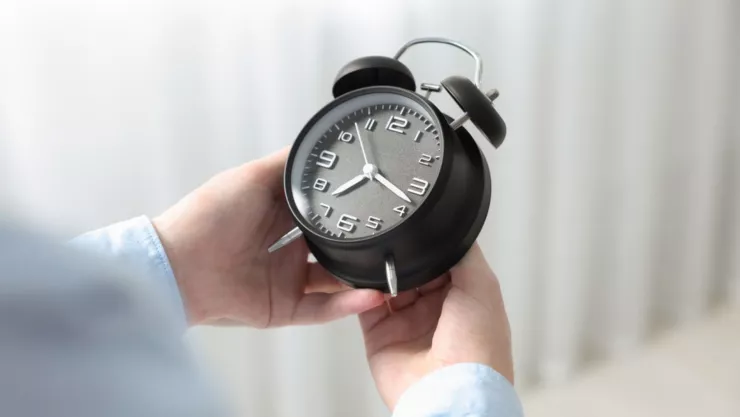 Una persona cambia la hora en su reloj de mesa.
