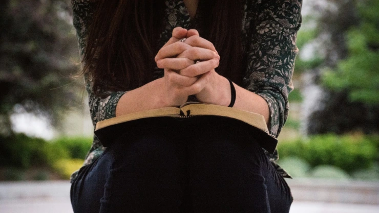 Mujer orando con biblia.