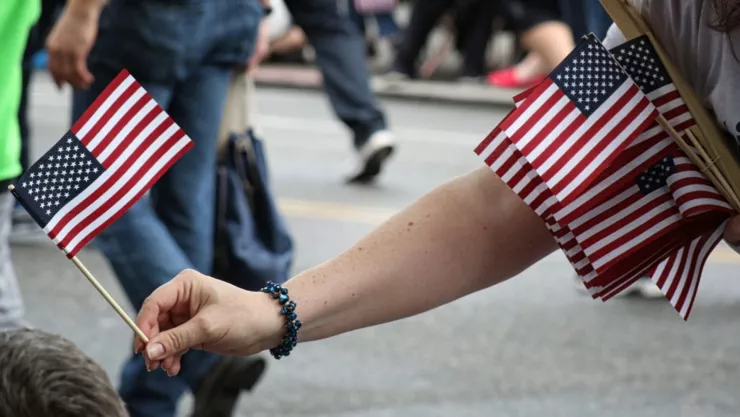 Una persona entrega banderas de Estados Unidos durante una celebración.