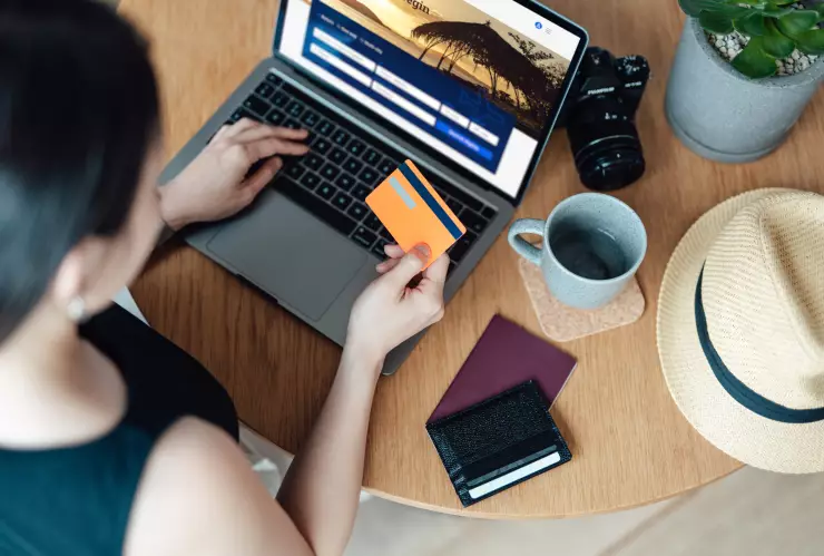 High angle view of young woman booking flight tickets online using laptop