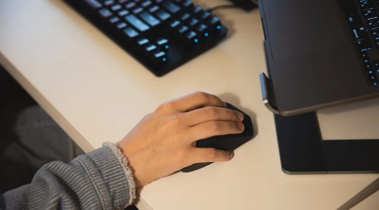 Una mano tomando el mouse de la computadora.