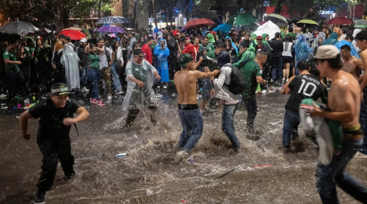 Aficionados se reúnen en la Ciudad de México - Ciudad de México , México - 24 de junio de 2026. Aficionados mexicanos juegan bajo la lluvia mientras celebran después del partido.