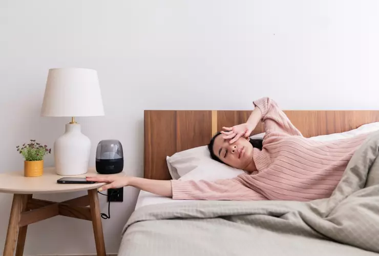 una mujer se levanta cansada y apaga su alarma