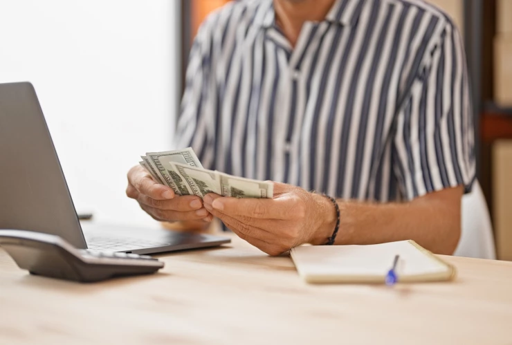 Una persona hace cálculos con dólares.
