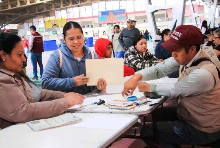 Madres de familia recibiendo la tarjeta de los beneficiarios de la beca Benito Juárez en México.