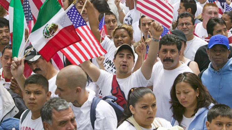 Ciudadanos latinos durante una protesta alzan banderas de México y EU
