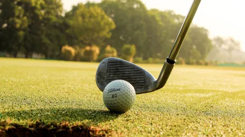 Un palo de golf a punto de golpear la pelota